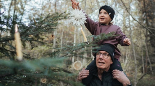 Ein Grossvater und eine Enkelin schmücken den Weihnachtsbaum.